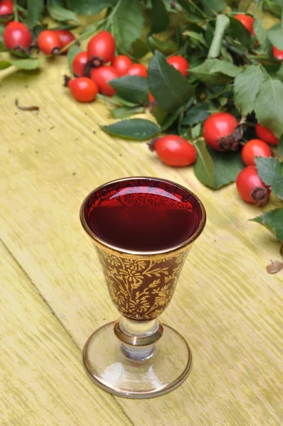 Rosehip fruit and alcoholic liquor in a glass — Stock Photo, Image