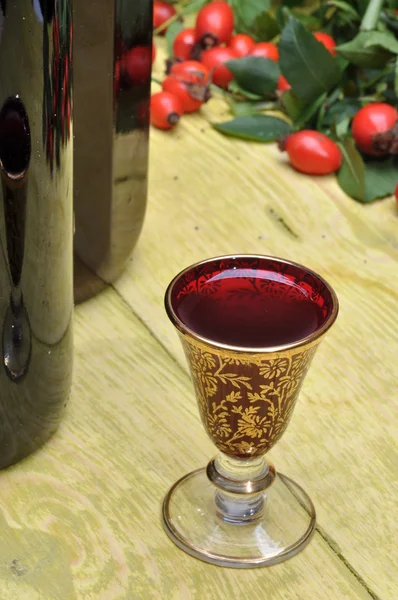 Een flessen drank, glas en rozenbottels fruit — Stockfoto