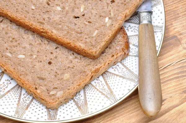 Plátky chleba s nožem na talíři — Stock fotografie