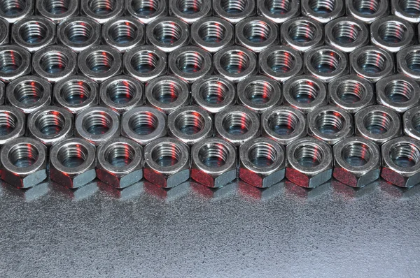 Tuercas metálicas brillantes sobre una superficie metálica — Foto de Stock