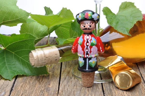 Parafuso decorativo húngaro, garrafa de vinho e copo de vinho na mesa de madeira com ramos verdes videira — Fotografia de Stock