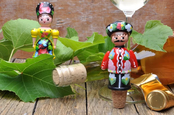 Hungarian decorative corkscrew, wine bottle and glass of wine on the wooden table with green twigs vine — Stock Photo, Image