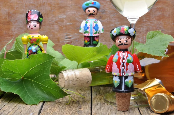 Cavatappi decorativi ungheresi, bottiglia di vino e bicchiere di vino sul tavolo di legno con ramoscelli verdi — Foto Stock