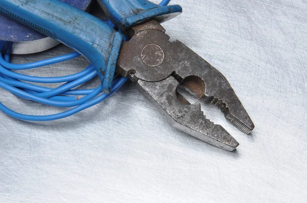 Pliers and cables on metal surface — Stock Photo, Image