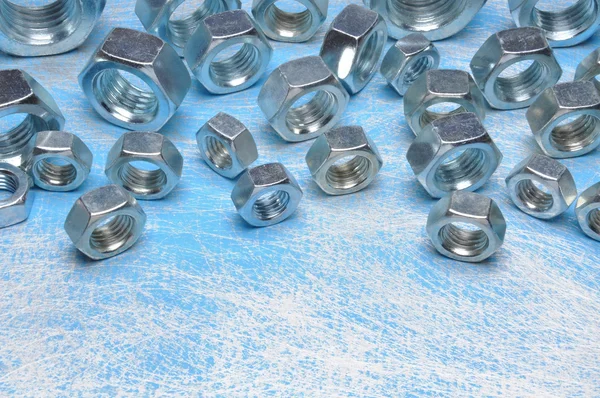 Steel nuts on blue metal background — Stock Photo, Image