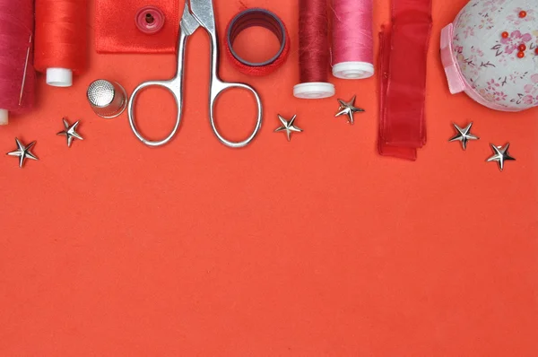 Sewing kit tool, scissors, thread and accessories on a red background — Stock Photo, Image