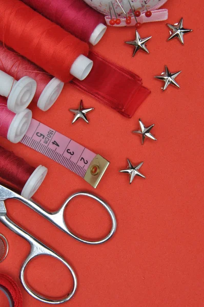 Sewing kit tool, scissors, thread and accessories on a red background — Stock Photo, Image