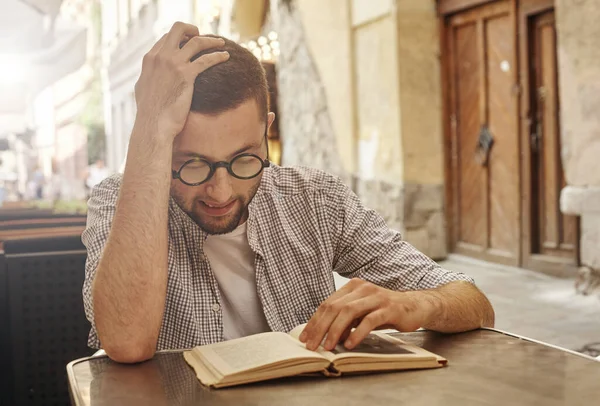 Étudiant assis et lisant un livre dans la rue dans un café — Photo