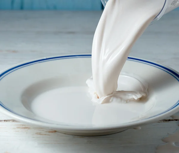 Cierre de la leche que se vierte en un plato — Foto de Stock