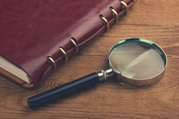 Red Notebook with a magnifier — Stock Photo, Image