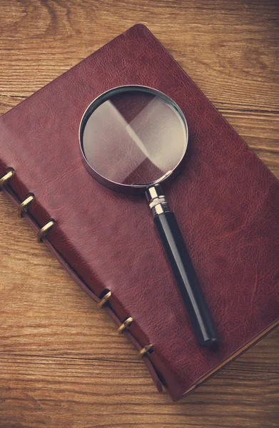 Notebook with a magnifier on table — Stock Photo, Image