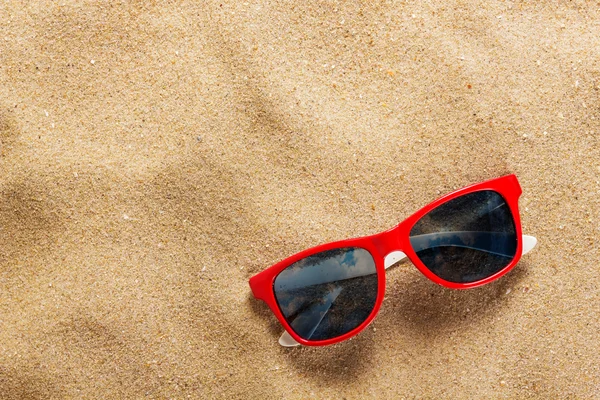 Zonnebril in het zand op het strand — Stockfoto