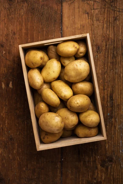 Aardappelen in vak op achtergrond — Stockfoto