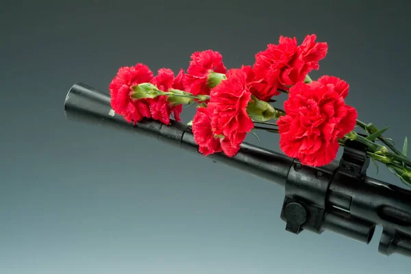 Machine gun and flowers on a studio background