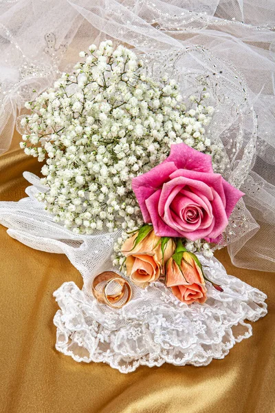 ファブリックの背景に2つの結婚指輪と花 — ストック写真