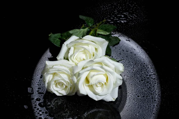 Bouquet of white roses and jewelry on a black glass background