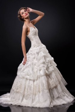 Siyah arka planda şık bir gelinlik içinde genç ve güzel bir kadın.