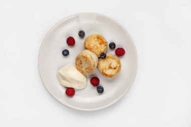 İzole edilmiş bir stüdyo arka planında bir tabakta peynirli kek ve farklı meyveler.