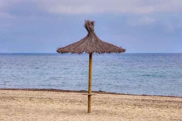 Sombrilla de paja en la playa de arena . — Foto de Stock