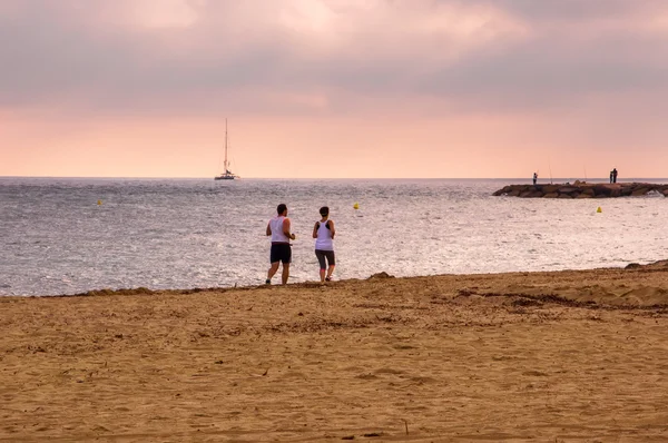 Hombre y mujer corren juntos en la playa . — Foto de Stock