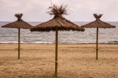 Üç saman şemsiye kum plajındaki.