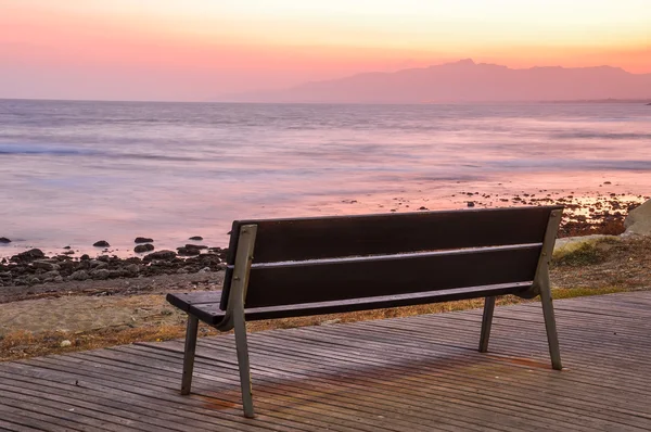 海辺の夕暮れ時の空のベンチ. — ストック写真