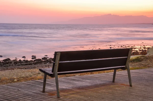 Banco vacío junto al mar al atardecer . — Foto de Stock