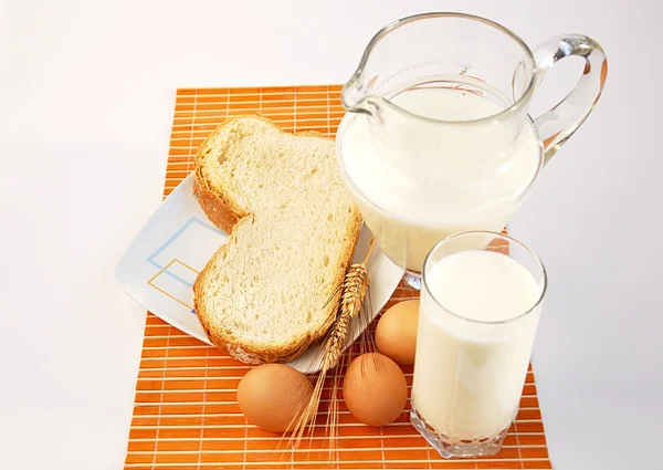 Krug mit Milch, Weizen, Brot und Eiern. — Stockfoto