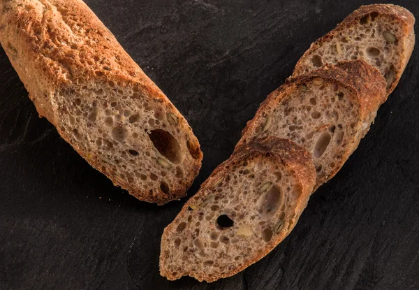 Segmenten van verse zelfgemaakte Alpine stokbrood geserveerd op zwarte leisteen plaat (lade). — Stockfoto