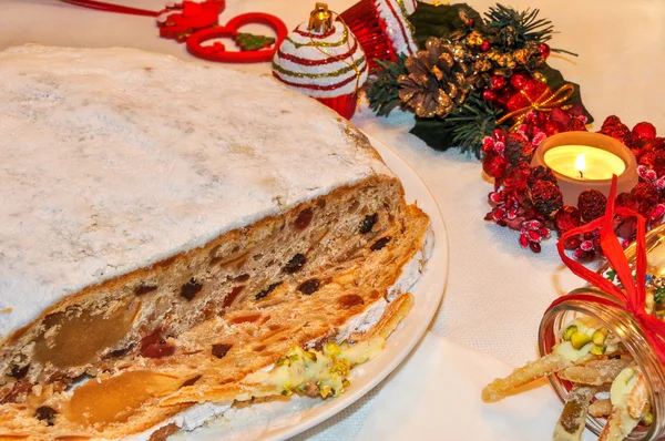 Christmas stollen, candied fruit, candle and decorations. — Stock Photo, Image