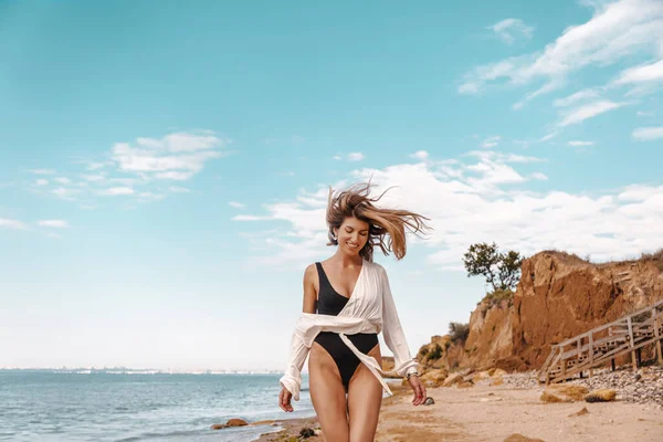 夏の日に砂浜でポーズをとる黒い水着と白いシャツを着た可愛い女性 — ストック写真
