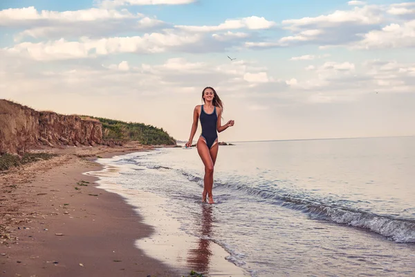 Glücklich Gebräunte Junge Frau Schwarzen Badeanzug Läuft Meerwasser Der Sandküste lizenzfreie Stockbilder
