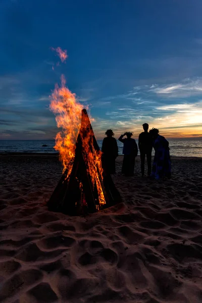 Persone irriconoscibili che celebrano il solstizio d'estate con falò sulla spiaggia — Foto Stock