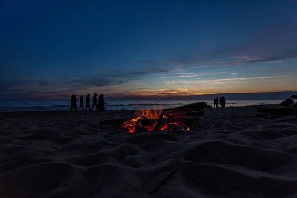 Unrecognisable people celebrating summer solstice with bonfires on beach