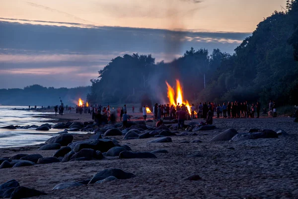 Persone irriconoscibili che celebrano il solstizio d'estate con falò sulla spiaggia — Foto Stock