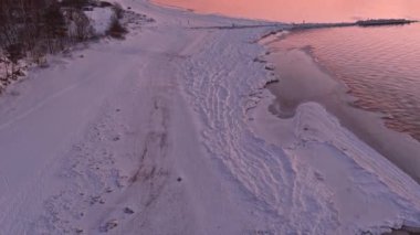 Donmuş deniz kıyısında sakin bir denizde gün batımı.