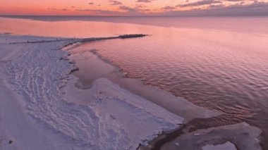 Donmuş deniz kıyısında sakin bir denizde gün batımı.