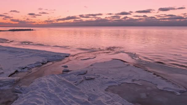 Auringonlasku tyynessä meressä jäätyneellä merenrannalla. — kuvapankkivideo