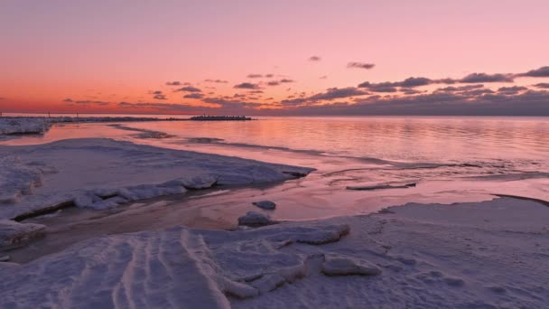 Solnedgång i ett lugnt hav med frusen havsstrand. — Stockvideo