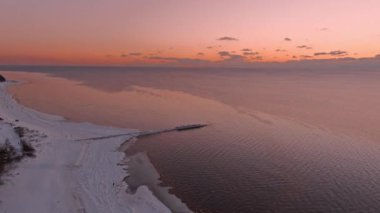 Donmuş deniz kıyısında sakin bir denizde gün batımı.