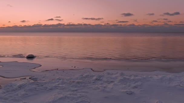 얼어붙은 해변 이 잔잔 한 바다에 떠 있는 일몰 광경. — 비디오