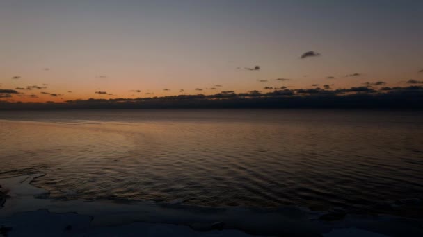 Solnedgång i ett lugnt hav med frusen havsstrand. — Stockvideo