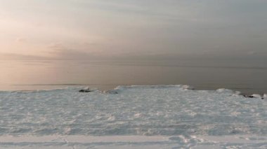Donmuş deniz kıyısında sakin bir denizde gün batımı.