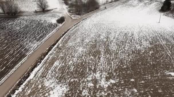 Αεροφωτογραφία με αγροτικό δρόμο και χιόνι καλυμμένα οργωμένα αγροτικά χωράφια — Αρχείο Βίντεο