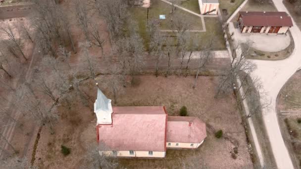 Malý vesnický kostel se zlatým kohoutem na vršku zvonice v lotyšském Umurze. Letecký pohled z dronu — Stock video