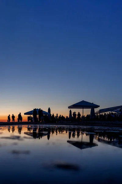 Gün batımında sahil barındaki kalabalık siluetleri — Stok fotoğraf