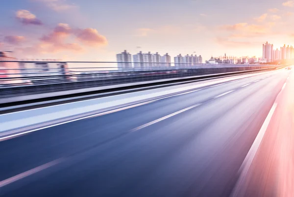 Bilkörning på motorväg vid solnedgången, rörelse suddig — Stockfoto