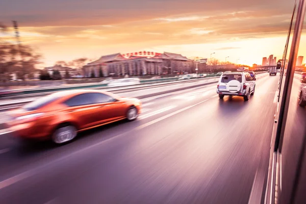 Bilkörning på motorväg vid solnedgången, rörelse suddig — Stockfoto