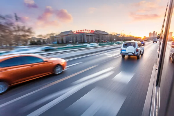 Bilkörning på motorväg vid solnedgången, rörelse suddig — Stockfoto