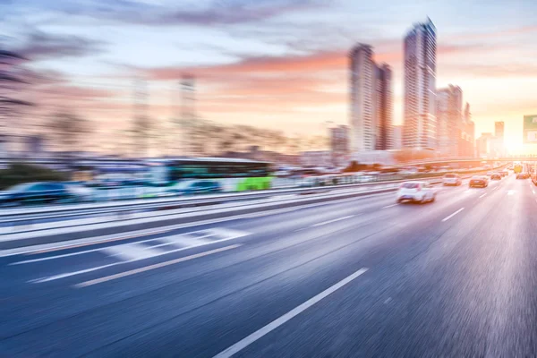 Coche conduciendo en la autopista al atardecer, desenfoque de movimiento — Foto de Stock